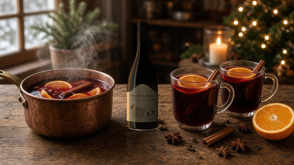 Garrafa de Quinta do Piloto Vinha dos Pardais Tinto ao lado de um tacho de cobre e canecas de vinho quente com laranja e canela
