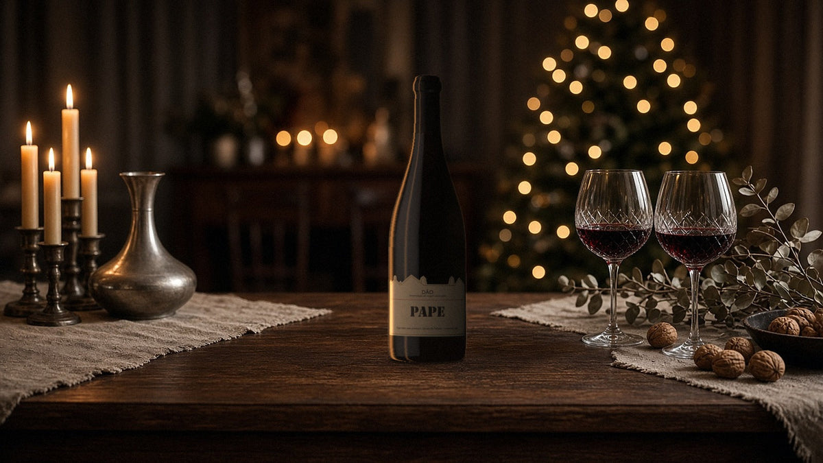 Botella mágnum de Pape 2020, tinto del Dão, en una mesa de Navidad a la luz de las velas con dos copas de vino tinto y nueces
